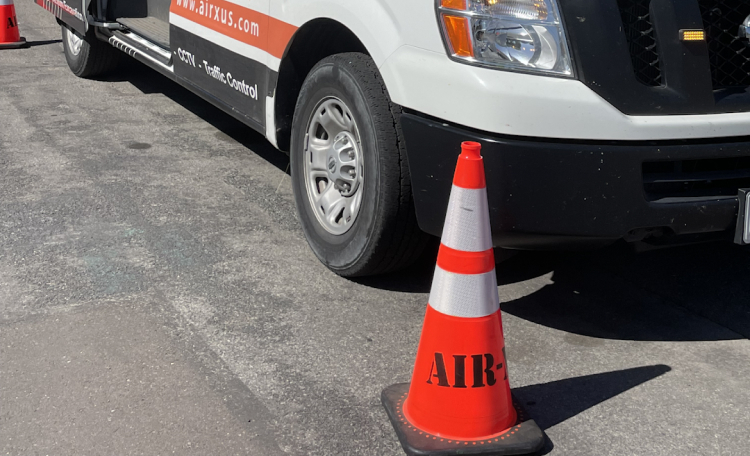 A vehicle driving by a traffic cone