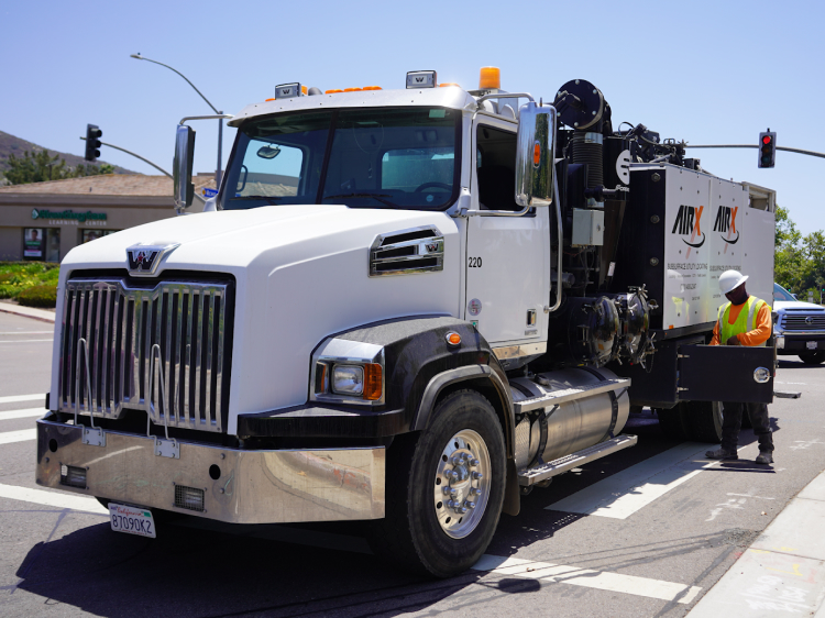 An AirX crew member using an instrument on an AirX truck